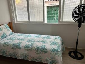 a bedroom with a bed and a fan next to a window at Novíssimo apt 1 quarto Centro frente à Prefeitura in Nova Friburgo