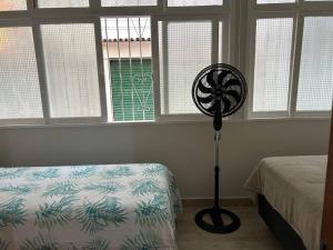 a bedroom with a bed and a fan in front of windows at Novíssimo apt 1 quarto Centro frente à Prefeitura in Nova Friburgo