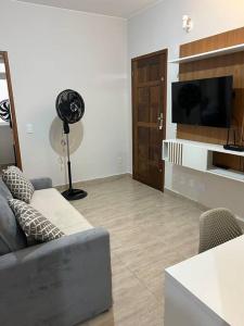 a living room with a couch and a flat screen tv at Novíssimo apt 1 quarto Centro frente à Prefeitura in Nova Friburgo