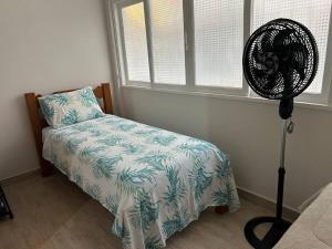 a bedroom with a bed and a fan next to a window at Novíssimo apt 1 quarto Centro frente à Prefeitura in Nova Friburgo