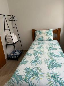 a bedroom with a bed with a blue and white blanket at Novíssimo apt 1 quarto Centro frente à Prefeitura in Nova Friburgo