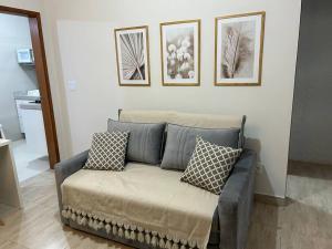 a couch in a living room with three pictures on the wall at Novíssimo apt 1 quarto Centro frente à Prefeitura in Nova Friburgo