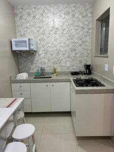 a kitchen with white cabinets and a stove top oven at Novíssimo apt 1 quarto Centro frente à Prefeitura in Nova Friburgo