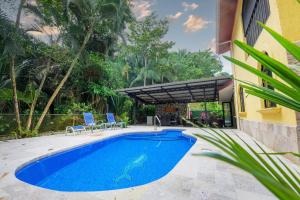 a swimming pool in front of a house with chairs and a building at Jungle & Beach Retreat Villa Tranquilo in Esterillos Este