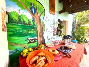 a table with food on it with a painting of a tree at Pousada 4 cantos in Corumbá