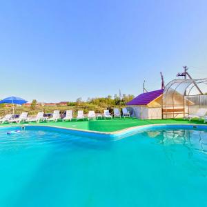 a large swimming pool with chairs and a greenhouse at Altyn Kun Hotel in Borovoye