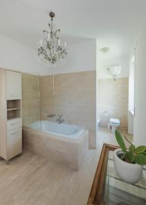 ein Badezimmer mit einer Badewanne, einem WC und einem Kronleuchter in der Unterkunft Villa Mara Appia antica in Rom