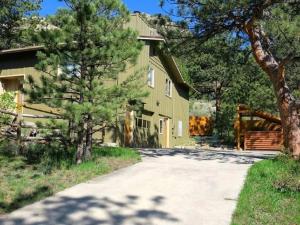 a yellow house with trees in front of a driveway at Bear House - EV #3073 in Estes Park