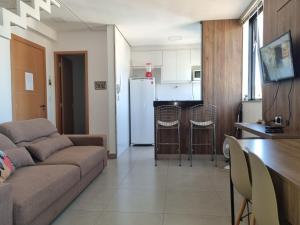 a living room with a couch and a kitchen at Apartamento luxo no centro in Ubá