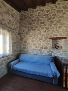 a blue couch in a room with a stone wall at Drymaia Chalet in Amfikleia