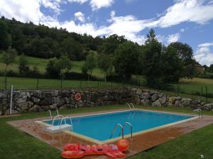 a swimming pool in a yard with a rock wall at Chalet turístico La Jenduda in Ojedo