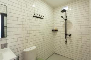 a white tiled bathroom with a shower and a toilet at Alam Nirwana in Kintamani