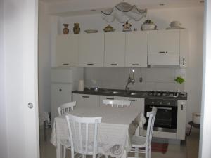 マリーナ・ディ・ラグーザにあるCasa Vacanze Le Roseのキッチン(白いキャビネットと白い椅子付きのテーブル付)
