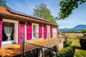 a house with pink doors and a balcony at Appt Cosy et chaleureux - La crinière in Le Poët