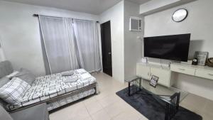 a living room with a couch and a flat screen tv at JTropics Plumera Mactan Near Airports, Malls and Beaches in Lapu Lapu City +8 photos