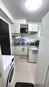 a kitchen with white cabinets and a washer at JTropics Plumera Mactan Near Airports, Malls and Beaches in Lapu Lapu City