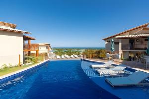 a swimming pool with lounge chairs and a resort at Village Super Charmoso Cond. Oahu Alto do Imbassaí in Imbassai