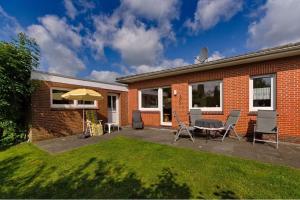 un patio avec une table, des chaises et un parasol dans l'établissement Ferienhaus Krüger, à Schillig