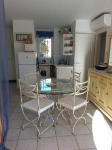 a kitchen with a glass table and two chairs at bleu marine in Bormes-les-Mimosas