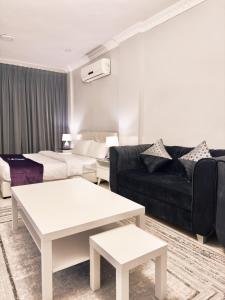 Una sala de estar con un sofá negro y una mesa. en SKY2030Tower, en Dammam