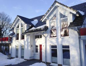 a white house with a red door in the snow at Viadukt in Willingen