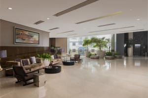 a lobby with couches and tables and potted plants at Embassy Suites by Hilton Santo Domingo in Santo Domingo