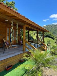 a wooden cabin with a porch with palm trees at Sítio vale das pedras in Barracão