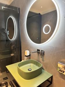 a bathroom with a green sink and a round mirror at Déco ArtRooms in Porto Cesareo