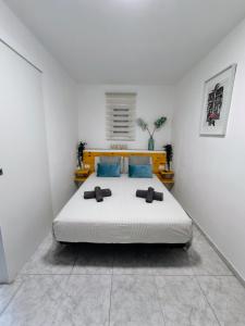 een witte slaapkamer met een groot bed met blauwe kussens bij Apartamento OCEAN PEARL in Corralejo