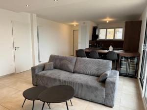 ein Wohnzimmer mit einem Sofa und Tischen sowie eine Küche in der Unterkunft Colocation appartement terrasse XXL Port Marianne in Montpellier