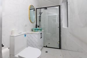 Un baño blanco con inodoro y ducha. en Glenelg Modern Studio, QBed,Wifi, en Glenelg