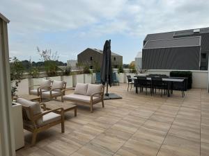 eine Terrasse mit Stühlen, Tischen und einem Sonnenschirm in der Unterkunft Colocation appartement terrasse XXL Port Marianne in Montpellier