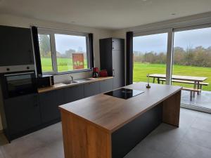 a kitchen with a counter and a table and windows at La maison d'Inès in Nassogne
