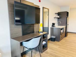 a room with a desk with a large television on a wall at Studio 6 Hornepayne, ON in Hornepayne