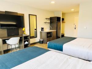 a hotel room with a bed and a desk with a television at Studio 6 Hornepayne, ON in Hornepayne