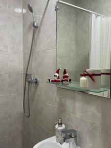 un bagno con doccia e decorazioni di Babbo Natale su una mensola di 'MONAS' mini apartments a Sombor