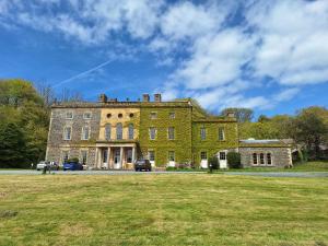 a large brick building with cars parked in front of it at Plas Nanteos Mansion in Aberystwyth