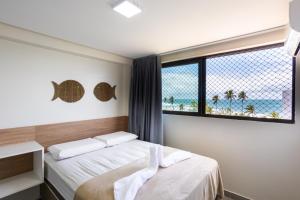 ein Schlafzimmer mit zwei Betten und einem Fenster mit Blick auf den Strand in der Unterkunft Capri Residence in Porto De Galinhas