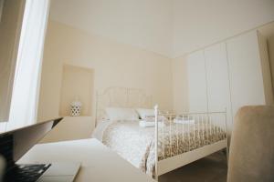 a white bedroom with a bed and a desk at Dimora Del Vicolo in Ostuni