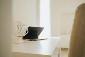 a laptop computer sitting on a white desk with a vase at Dimora Del Vicolo in Ostuni