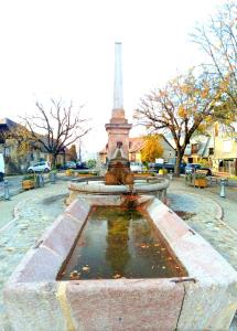 a fountain in a park with a monument in the background at petite maison cosy cœur village in Chorges