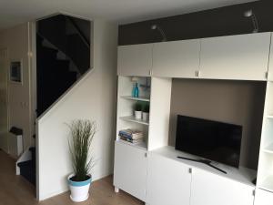 a living room with white cabinets and a flat screen tv at Appartement Anker in Hollum