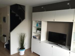 Una sala de estar con gabinetes blancos y un televisor de pantalla plana. en Appartement Anker, en Hollum