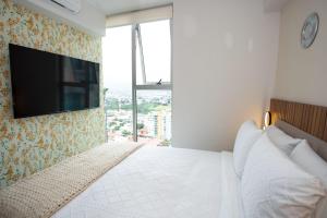 a bedroom with a bed with a tv on the wall at Serenitas at 20, City Views and Wonderland Vibes! in Hatillo