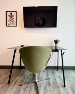 a table with a green chair and a television on a wall at Serenity at 12, City Views and Wonderland Vibes! in Hatillo