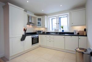 a white kitchen with white cabinets and a window at The Pyjama Factory in Bushmills