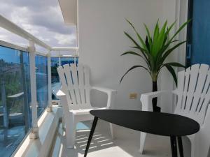 a table and two white chairs and a plant on a balcony at Rincón de Tranquilidad in Bayahibe