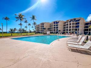 a resort swimming pool with lounge chairs and palm trees at Crescent Beach Apt Ocean View in Humacao