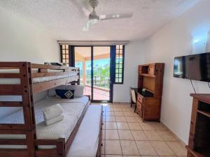 a room with two bunk beds and a television and a balcony at Crescent Beach Apt Ocean View in Humacao +35 photos