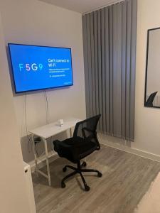 a desk and a chair in a room with a screen at Large Ensuite Room in Manchester with Free Parking in Manchester